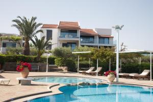 a swimming pool with chairs and a building in the background at Artemis Village Apartments & Studios in Stavros