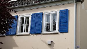 two windows with blue shutters on a building at Atelier in Kassel