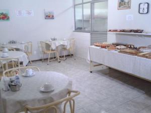 a kitchen with two tables and tables with pastries at Hotel São João in Campinas