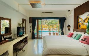 a bedroom with a bed and a tv and a window at Riad Hua Hin in Hua Hin