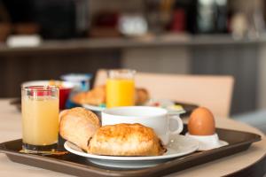 bandeja con alimentos para el desayuno y bebidas en una mesa en ACE Hôtel Travel Athée sur Cher, en Athée-sur-Cher