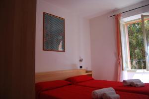 a bedroom with two red beds and a window at Appartamenti Corneliani II in Sirmione
