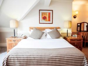 a bedroom with a large bed with a checkered blanket at Cottons Hotel and Spa in Knutsford