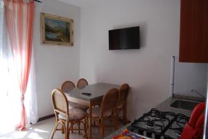 une salle à manger avec une table, des chaises et une télévision dans l'établissement Appartamenti Corneliani II, à Sirmione