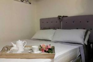 カリアリにあるMonolocale Stampaceのベッドの上に紅茶セットと花を用意したトレイ