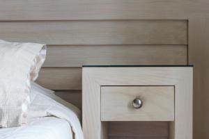 ein Bett mit einem Kopfteil aus Holz und einem Nachttisch mit einer Schublade in der Unterkunft Esperance 1 in Ermoupoli