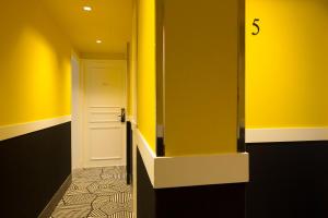 a hallway with yellow walls and a white door at Hotel Haussmann Saint Augustin in Paris