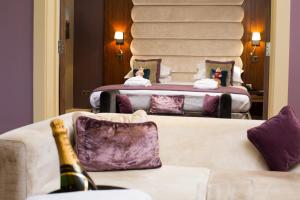 a room with two beds and a couch with a bottle of champagne at The Mere Golf Resort & Spa in Knutsford