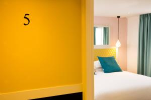 a bedroom with a bed with a yellow wall at Hotel Haussmann Saint Augustin in Paris