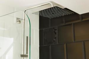 a shower head in a bathroom with a black tile wall at Hotel Haussmann Saint Augustin in Paris