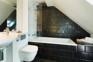 a bathroom with a toilet and a sink and a bath tub at Hotel Haussmann Saint Augustin in Paris