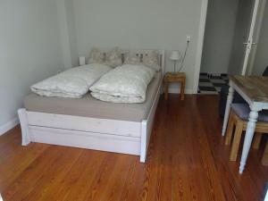 ein Bett mit weißer Bettwäsche und Kissen auf einem Holzboden in der Unterkunft City Appartement in Baden-Baden