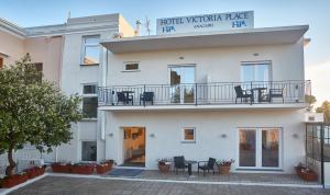 a white building with a balcony and tables and chairs at Hotel Victoria Place in Anacapri