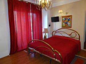 a bedroom with a bed with red curtains and a chandelier at Vila Smarald Apartments in Neptun