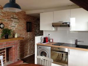 a kitchen with white cabinets and a brick wall at Le Duplex des Eclusiers in Redon