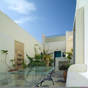 a patio with a glass table in front of a building at Dar Hayder-la Medina in Tunis