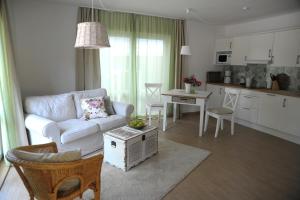 a living room with a white couch and a kitchen at SEASIDE APARTMENTS - DREAMY GREEN in Eckernförde