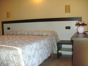 Un dormitorio con una cama y una mesa con un jarrón. en Agriturismo Le Gazze, en Camposanto