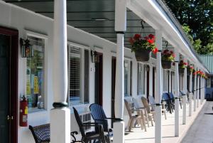 eine Reihe von Stühlen auf einer Veranda mit Blumen in der Unterkunft Rock Ledge Motel in Alexandria Bay