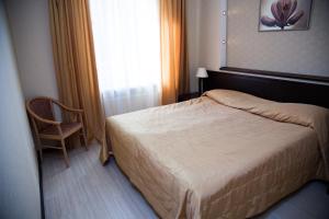 a bedroom with a bed and a chair and a window at Premier Hotel in Kostroma