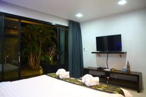 a hotel room with a bed and a flat screen tv at Baan Norkna Bangtao in Bang Tao Beach