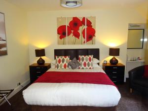 a bedroom with a bed with a red blanket and two lamps at Adelphi Villa in Oban