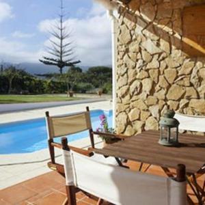 a wooden table and chairs next to a stone wall at Vinha da Quinta in Sintra
