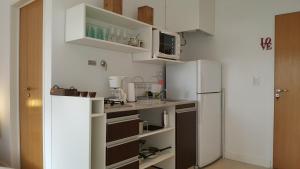 una pequeña cocina con armarios blancos y nevera. en Loft Almagro en Buenos Aires