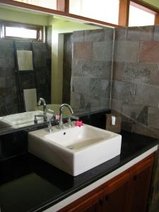 a bathroom with a white sink and a mirror at Villa Kawan in Tanah Lot