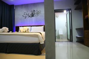 1 dormitorio con 1 cama grande y pared morada en Baan Norkna Bangtao en Bang Tao Beach