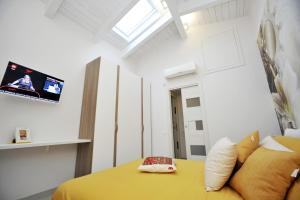 1 dormitorio con 1 cama amarilla y TV en Luxury Apartment Della Marca, en SantʼAntonio Abate