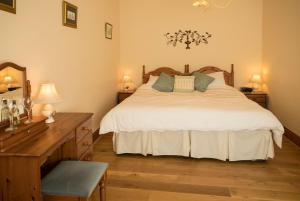 een slaapkamer met een bed, een dressoir en een bureau bij Forda Farm Bed & Breakfast in Holsworthy
