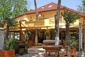 a building with tables and palm trees in front of it at Voyage Residence in Mamaia