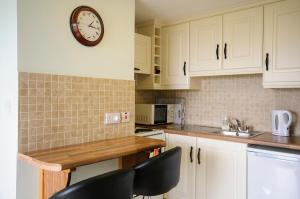 a kitchen with white cabinets and a clock on the wall at Seabreeze Junior Suite Renvyle in Renvyle