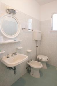 ein Badezimmer mit einem Waschbecken, einem WC und einem Spiegel in der Unterkunft Villa San Francesco in Misano Adriatico