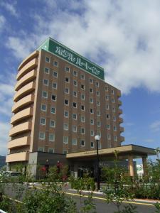 a hotel with a green sign on top of it at Hotel Route-Inn Suwa-Inter2 in Suwa