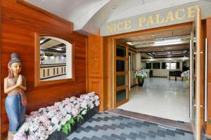a woman standing in front of a nice palace with flowers at Nice Palace Hotel in Bangkok