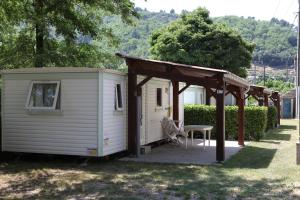 a small white shed with a pergola at Camping La Charderie in Pont-de-Labeaume
