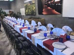 a long table with red and white table cloths and chairs at La Puerta de la Ribera in Sardón de Duero