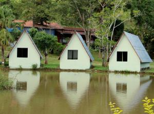 um grupo de três casas sentadas numa massa de água em Pousada do Lago Ltda em Conceição do Mato Dentro