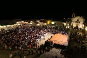 a crowd of people standing around a stage at night at La Casa di Angelica Marzamemi in Marzamemi