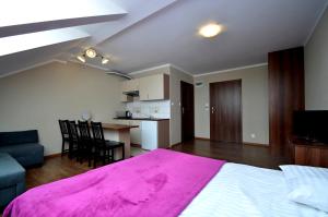 a bedroom with a large pink bed and a kitchen at Pensjonat Ślepowron in Międzywodzie
