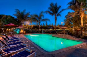 una piscina con sillas y árboles por la noche en University Park Inn & Suites, en Davis