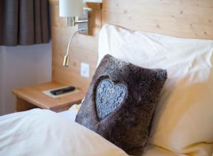 a bed with a pillow and a clock on it at Hotel Edelweiss Superior in Mürren