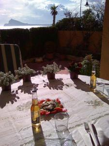 una mesa con dos botellas de cerveza y verduras. en Apartamento Mascarat vistas al mar, en Altea