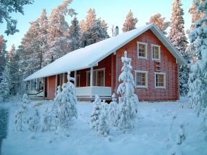 a red house with a snow covered tree in front of it at Riekko Chalet in Rovaniemi