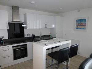 a kitchen with white cabinets and black counter tops at Apartment on the beach in Edinburgh