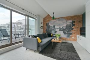Apartamenty Gdańsk EU - Waterlane في غدانسك: غرفة معيشة مع أريكة وجدار من الطوب