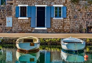 two boats sitting in the water in front of a house at Apartmani Bavaria in Vrboska