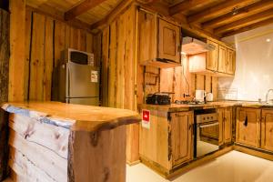 cocina con armarios de madera y nevera en Huilo Huilo Apartamentos Club Huillín, en Reserva Biológica Huilo Huilo